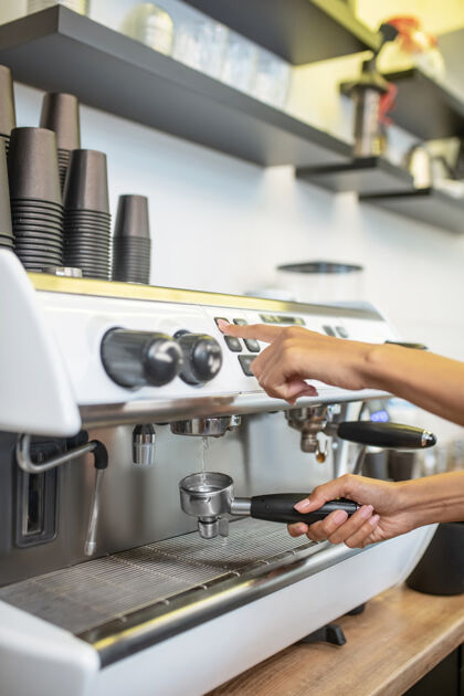 无脸咖啡机 女咖啡师咖啡机控制面板附近带过滤器支架的专业手 没有脸面板咖啡馆咖啡