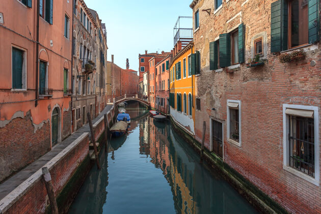 旅游船在威尼斯五颜六色的历史建筑之间的狭窄运河上度假城市贡多拉