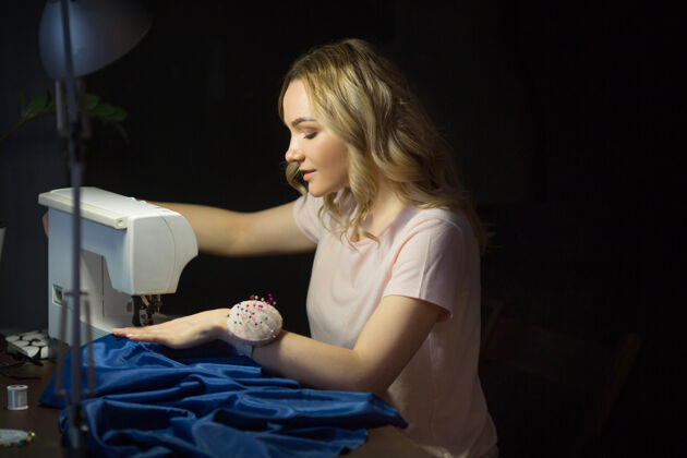缝纫漂亮的小女孩晚上上班时在缝纫机上缝衣服私人教练裁缝女人
