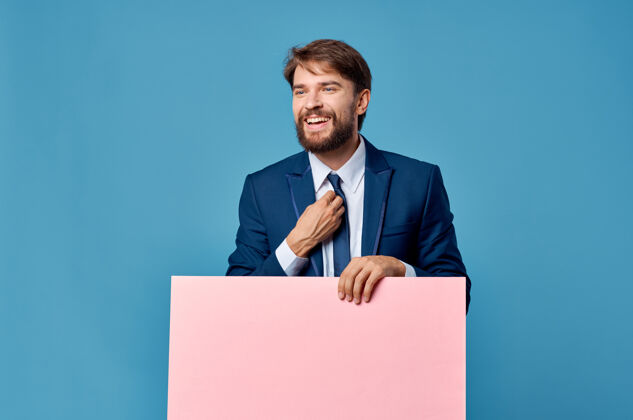 人商人拿着蓝色背景的粉红色宣传广告牌背景展示男性