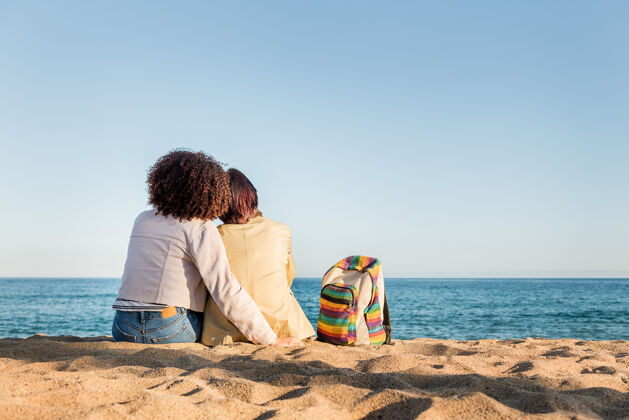 背部两个同性恋女孩坐在沙滩上朋友女性感觉