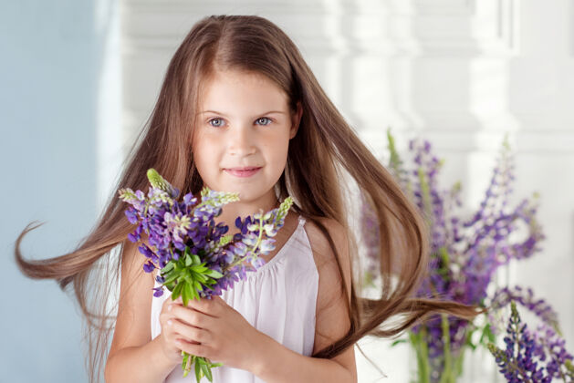 花束可爱的小女孩带着一束鲜花的肖像花看对着镜头羽扇豆可爱快乐