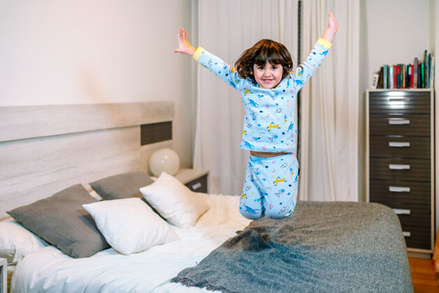 兄弟睡前穿着睡衣 张开双臂跳在床上的孩子非常开心关系睡衣小