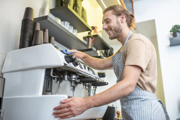湿巾咖啡机 清洁快乐穿着围裙的人在咖啡馆里小心地擦咖啡机简介清洁积极