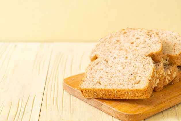 烘焙木桌上的全麦面包片面包屑种子面包