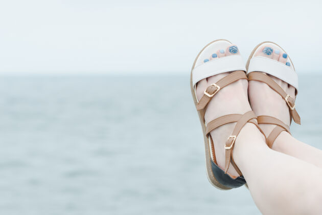皮肤穿着凉鞋的女性脚 在海洋背景上修指甲女孩脚户外