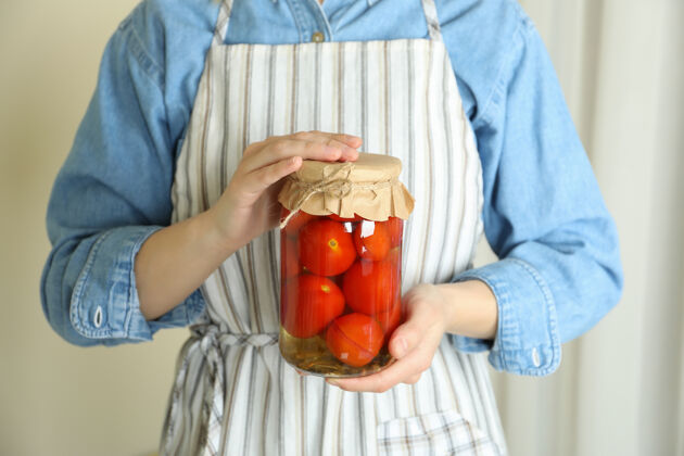 罐头围裙里的女人拿着一罐腌番茄自制番茄女性