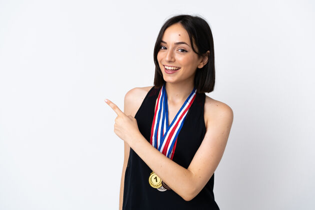 冠军年轻女子拿着奖牌孤立地指着旁边的白色指点着赠送的产品女性牙齿奖牌