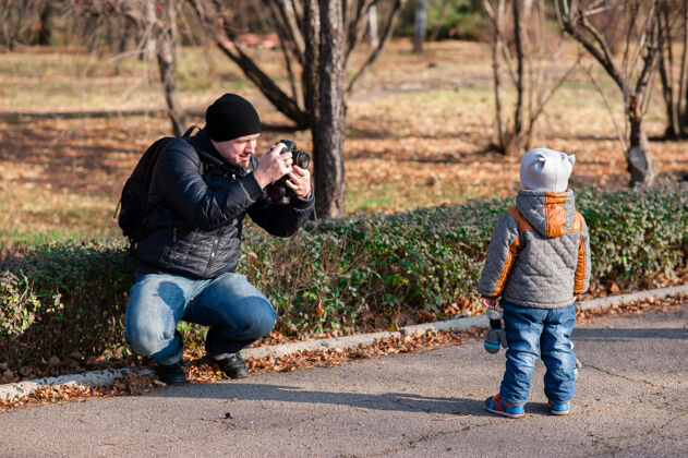 孩子爸爸在公园给儿子拍照年轻玩耍男孩