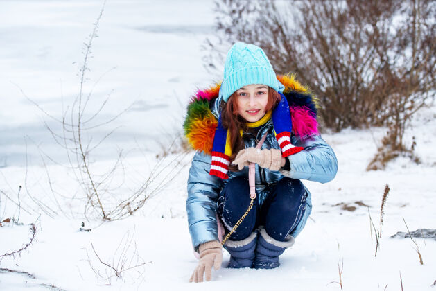 肖像冬日少女的画像在她的温暖服装女孩在下雪的天气里戴着蓝色的帽子和围巾女孩少年季节