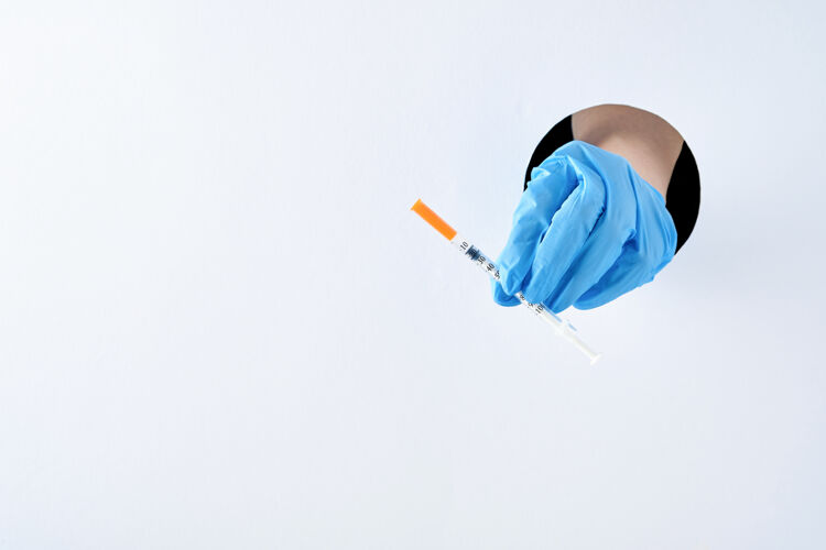 疫苗预防冠状病毒疫苗在防护医用蓝手套中手穿白纸洞.疫苗接种预防传染病的疫苗防护疾病药品