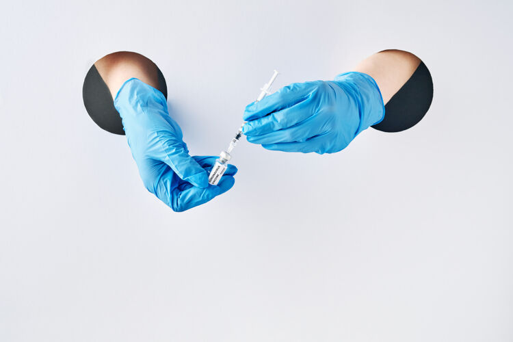 药品预防冠状病毒疫苗在防护医用蓝手套中手穿白纸洞.疫苗接种预防传染病的疫苗流行病手疾病