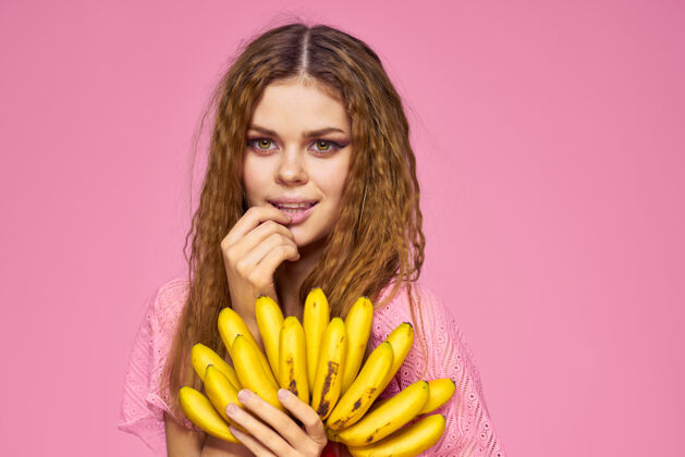 饮料女人用香蕉卷发水果生活方式亮丽妆容粉墙性感时尚红唇