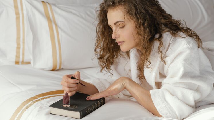 书籍女人在床上涂指甲油室内模特自我护理