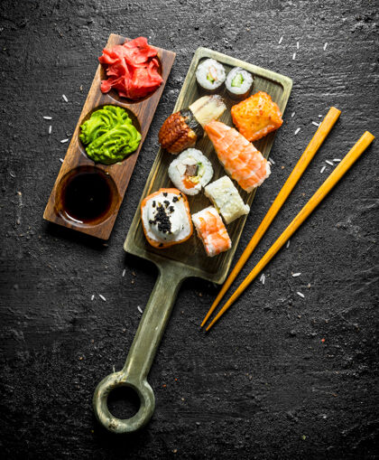 传统把寿司 面包卷和肉饼放在砧板上 用筷子和筷子酱汁黑色乡村餐桌乡村鲑鱼寿司