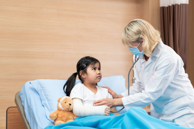 咨询儿科医生用听诊器给一个躺在床上的小女孩做检查生病医院儿童