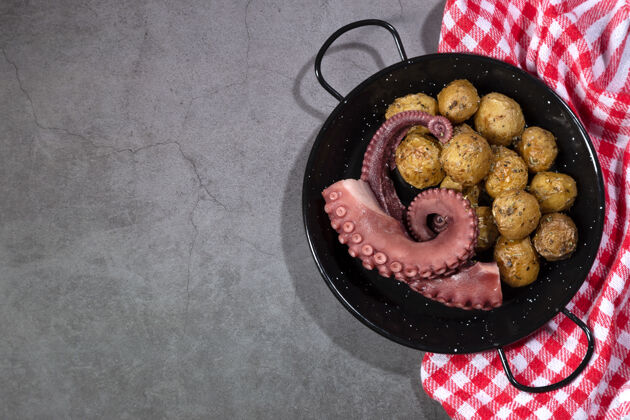 触角炖章鱼触须在一个煎锅板上黑暗的背景顶视图与复制空间螺旋形海鲜食物