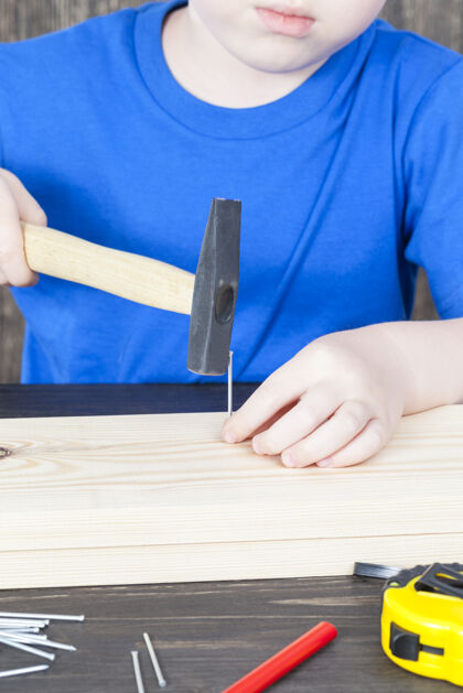 玩一个小男孩正在建一个木制的鸟舍 在木板上钉钉子鸟舍职业技能