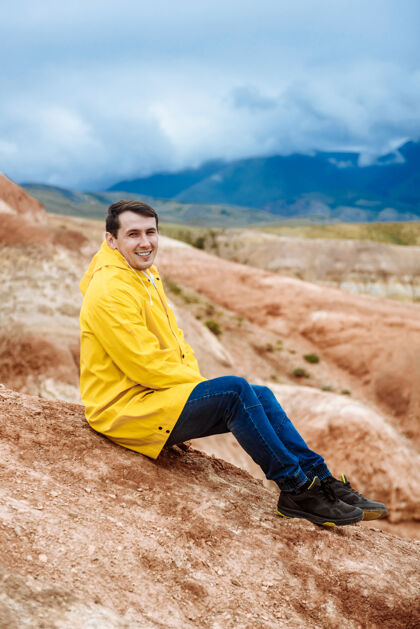 游客年轻快乐的游客西丁穿着黄色雨衣在彩色的山上快乐人人