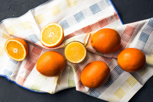 水果一张黑桌子上放着新鲜的橙汁和橙子橙子玻璃柑橘