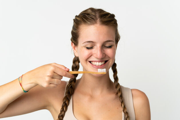 成人一位年轻的白人妇女 戴着牙刷 表情愉快 被隔离在白色背景下牙科早晨卫生