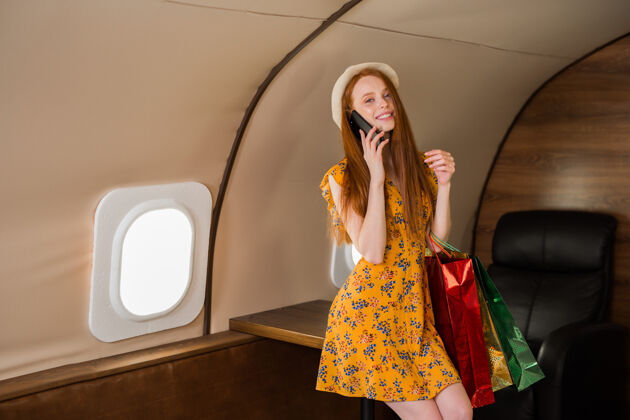 年轻穿着黄色连衣裙的漂亮年轻女子乘坐私人飞机带着包裹商务女性飞机包