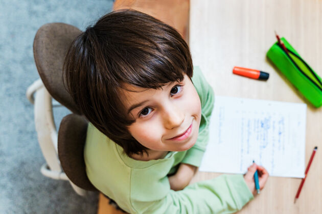 独自小男孩坐在桌子旁做作业家集中儿童写作练习很高兴在家上学概念桌子专注房子