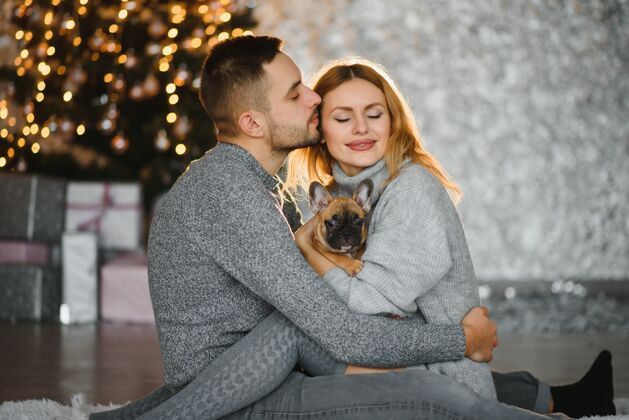 毛衣一对年轻夫妇在圣诞树前拥抱的照片拥抱男朋友在一起