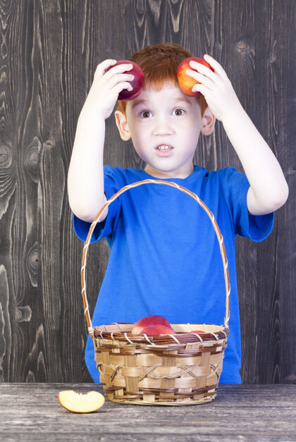 欧洲一个红头发的欧洲男孩在他放在头附近的成熟桃子里玩耍 特写镜头头发男孩头