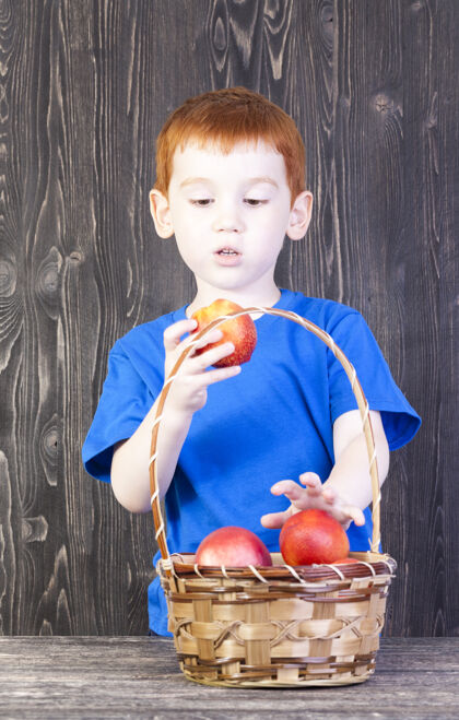 测试男孩看了看手里的油桃 桌上有一个篮子 里面放着其他的油桃和桃子发现水果线