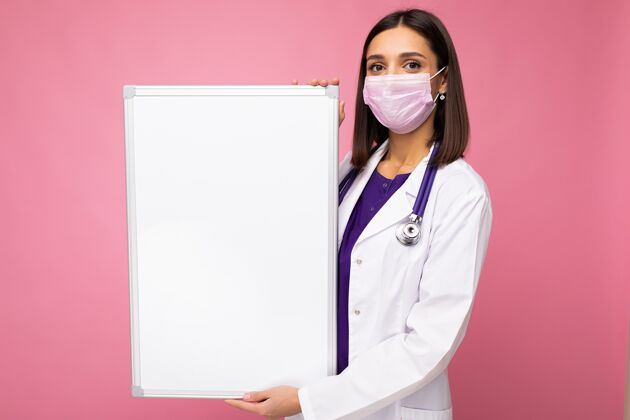 防护一名女医生 身穿白大褂 戴着口罩 手里拿着空白板 空白板上有文字隔离的复印空间背景.冠状病毒概念白板黑发青年