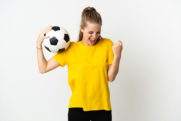 休闲年轻的白种人女子与足球庆祝胜利孤立的白色背景训练女子青年