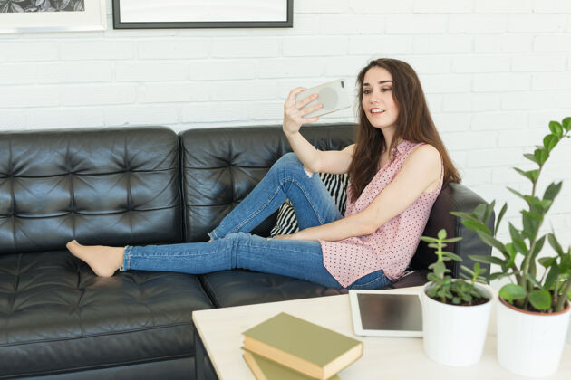 使用科技 美丽和人的概念-年轻微笑的女人试图用智能手机拍照 躺在沙发上抚摸她的头发女士休闲视频