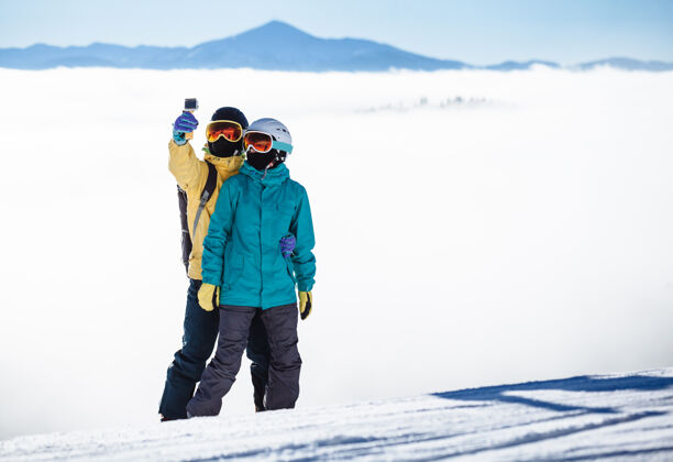 高峰滑雪者在山上用智能手机拍照采取成人雪
