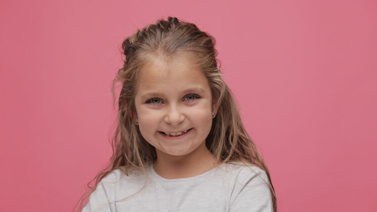 特写粉红色的小女孩的特写肖像背景可爱卷发女孩微笑着看着镜头童年脸眼睛