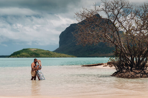 女人一个穿着泳衣的女孩和一个穿着短裤的男人站在毛里求斯岛上的莫恩山的背景下谎言家庭情侣