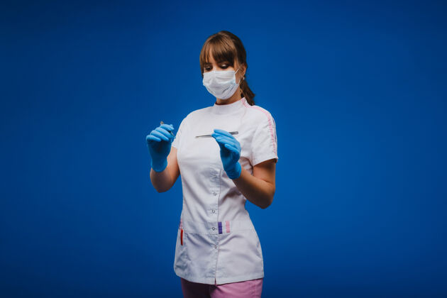 外科一位年轻貌美的女医生手持手术刀 直视手术台照相机.概念医疗 治疗和手术肖像一个蓝色背景的医生职业外科医生女性