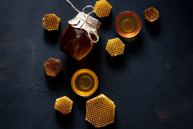 蜜蜂黑桌子上放着蜂窝状的蜂蜜罐滴水棒自然