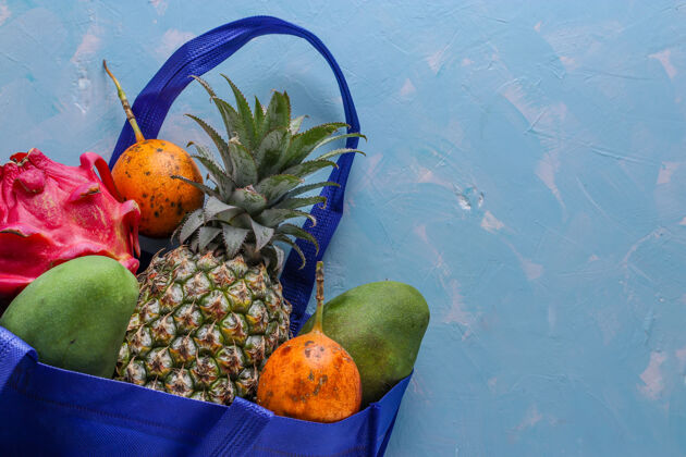 地球零浪费的概念 蓝色购物纺织袋与新鲜的热带水果：芒果 菠萝 龙和西番莲果 水平方向减少袋西番莲