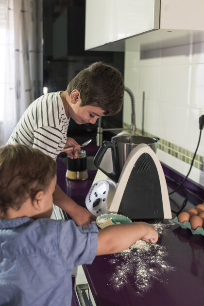 家庭两个孩子在用厨房机器人做煎饼两个煎饼男孩