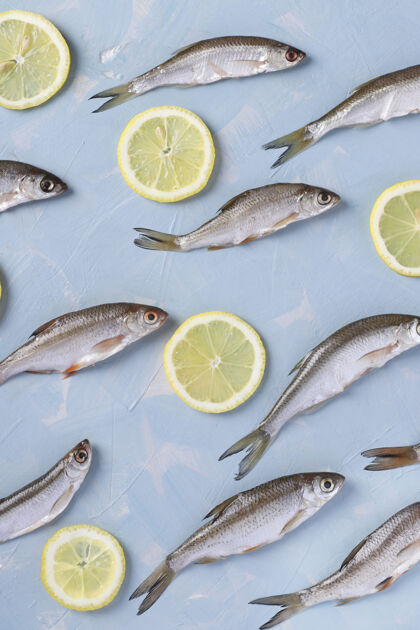 铺设蓝色表面上柠檬片的小鱼图案 俯视图 垂直方向不同成分餐厅