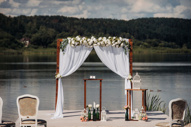 堤岸绿色街道上的婚礼草坪装饰用鲜花装饰拱门以庆祝仪式仪式湖泊装饰