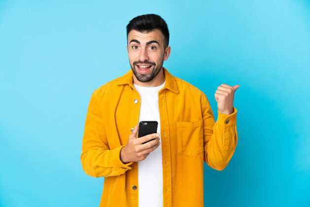 男性一个白人男子在蓝色背景下用手机指着侧面男人大笑快乐