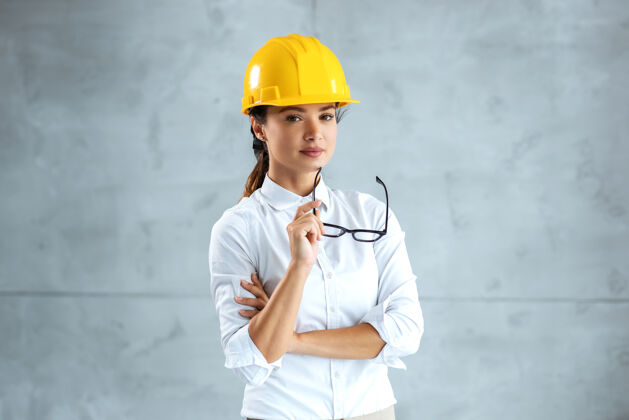 肖像头戴头盔的女建筑师站着看摄像机的画像成功主管雇员
