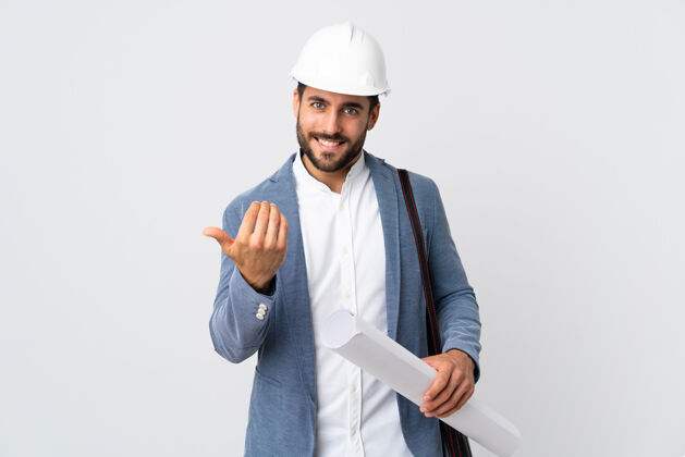 工程师年轻的建筑师戴着头盔 拿着隔离在白色地板上的蓝图 邀请他来手高兴你来了工业学生工人