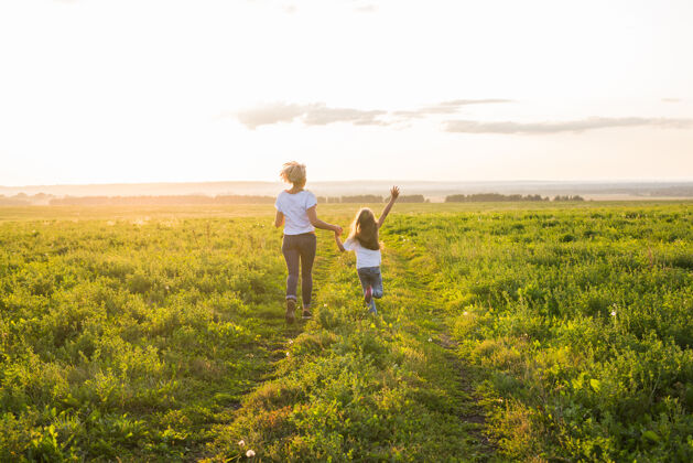 自由家庭 暑假和假期的概念-小女儿和妈妈在夏天的田野里奔跑乡村跑步风景