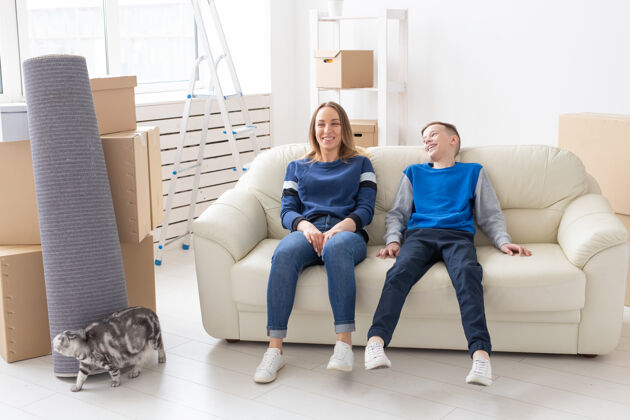 公寓快乐美丽的年轻单身母亲和一个积极向上的儿子正坐在沙发上 他们的身旁家庭欢迎建筑