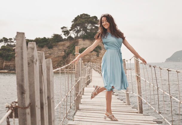 天空年轻快乐的女人在海边的桥上 夏日时光奢华热带海洋