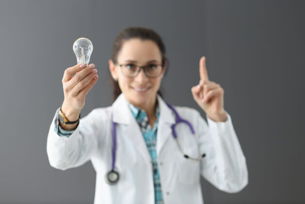 专业女医生手里拿着灯泡 露出食指向上新建医疗理念头脑风暴医生健康