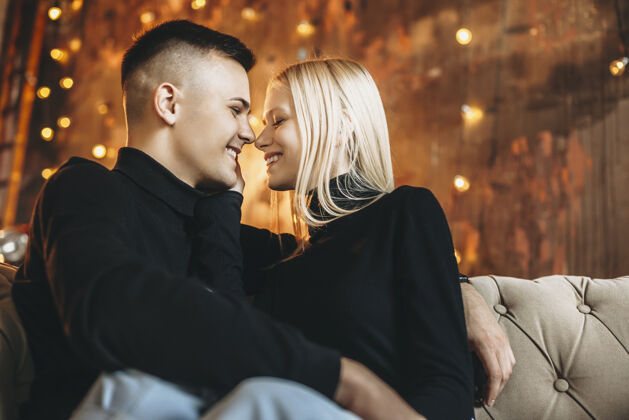 男人一对美丽的年轻夫妇坐在沙发上拥抱的侧视图关系看情人节